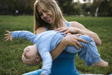 Verspielte blonde Frau mit Sohn im Park - YBF00294