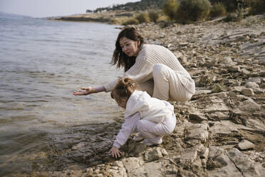 Happy mother playing with daughter by lake - YBF00299