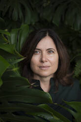 Beautiful woman amidst leaves in botanical garden - VRAF00222