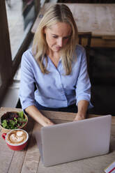Blonde Freiberuflerin arbeitet am Laptop in einem Café - ASGF04690