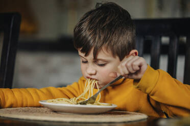 Hungriger Junge isst Nudeln zu Hause - VSNF01415