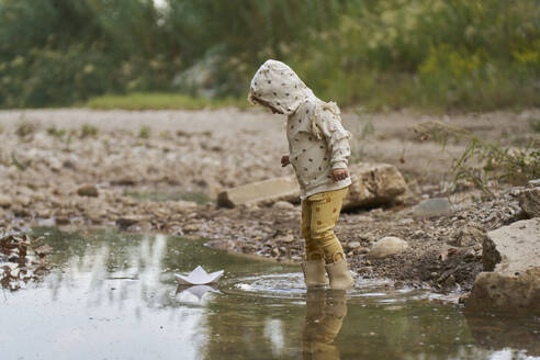 Mädchen mit Papierboot schwimmt auf Wasserpfütze - ANNF00597