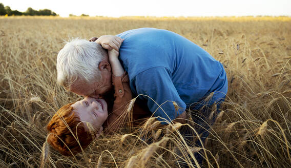 Happy grandson embracing grandfather in wheat field - MBLF00138