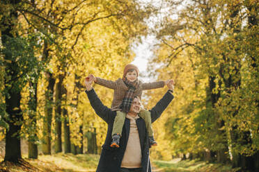 Glücklicher Vater trägt seinen Sohn auf den Schultern im Herbstpark - VSNF01416