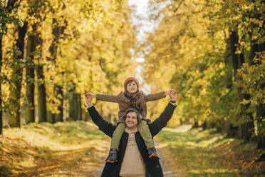 Vater trägt seinen Sohn auf den Schultern und hat Spaß im Herbstpark - VSNF01420