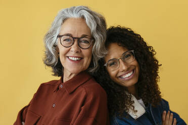 Lächelnde Mutter und Tochter mit Brillen vor gelbem Hintergrund - EBSF04028