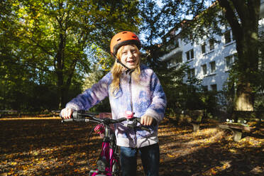 Lächelndes Mädchen mit Fahrrad im Park - IHF01827