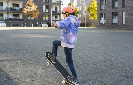 Mädchen mit Helm macht Ollie auf Skateboard - IHF01833