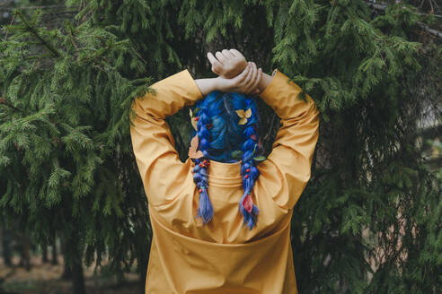 Carefree woman standing with arms raised in front of trees - YTF01383