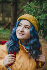Lächelnde Frau mit Rucksack und Erkundung im Wald - YTF01409