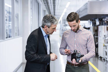 Engineers examining machine part in industry - DIGF20983