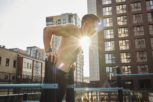 Shirtless man doing exercise on parallel bars - MRPF00002