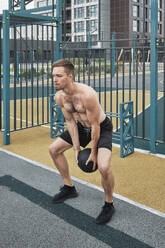 Aktiver Mann beim Training mit Medizinball im Fitnessstudio - MRPF00004