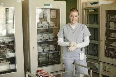 Lächelnde Laborantin im Blutbankraum stehend - KPEF00292