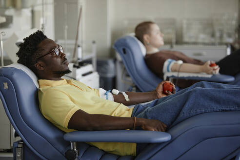 Mann auf einer Liege liegend bei einer Bluttransfusion - KPEF00294