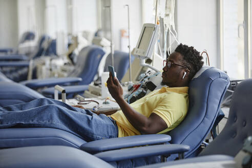 Mann beim Blutspenden und mit Smartphone - KPEF00317