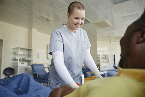 Lächelndes medizinisches Personal mit Spender im Blutspendezentrum - KPEF00323