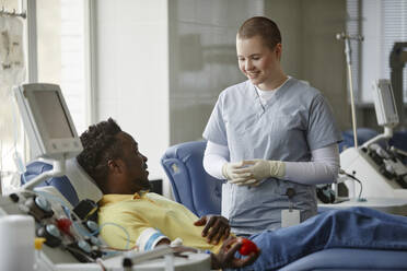 Arzt mit verschränkten Händen im Gespräch mit einem Blutspender in der Mitte - KPEF00325