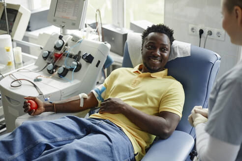 Lächelnder Spender im Gespräch mit medizinischem Personal im Blutspendezentrum - KPEF00326