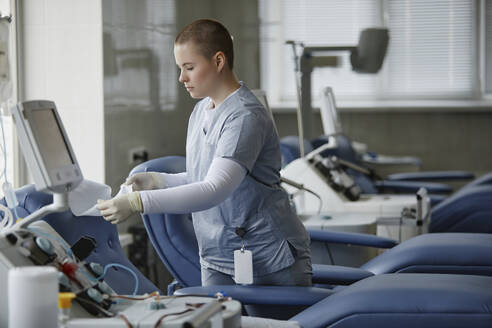 Mitarbeiter des Gesundheitswesens bei der Vorbereitung der Liege im Blutspendezentrum - KPEF00330