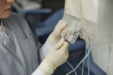 Medizinisches Personal beim Anbringen von Blutentnahmeröhrchen an Beuteln - KPEF00335