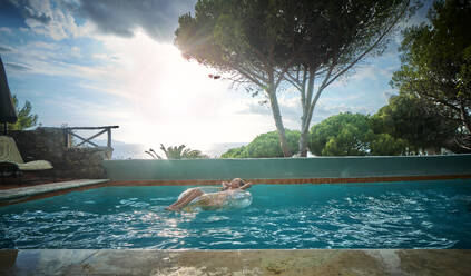 Mädchen mit aufblasbarem Schwimmring entspannt sich im Pool - DIKF00774