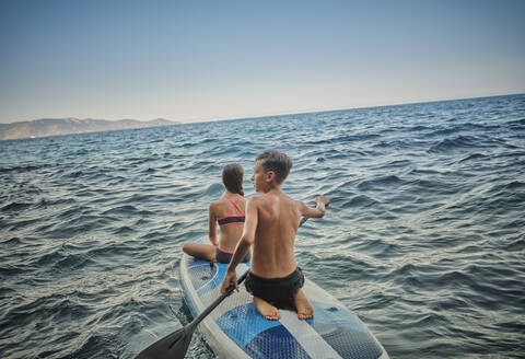 Boy paddling with sister in sea - DIKF00776