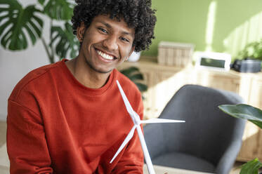 Smiling engineer with wind turbine model at home office - ALKF00821