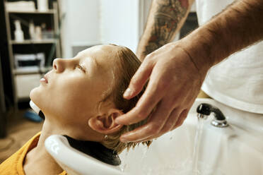 Friseurin wäscht die Haare eines Kunden im Friseursalon - MRPF00015