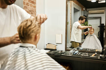 Friseur schneidet einem Kunden die Haare vor dem Spiegel im Salon - MRPF00016