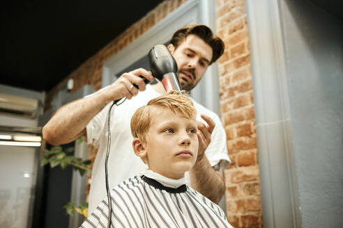 Friseur föhnt das Haar eines Kunden im Salon - MRPF00017