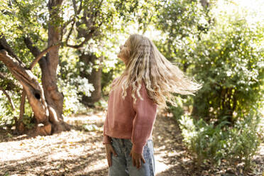 Lächelndes Mädchen mit langen blonden Haaren im Park stehend - LMCF00678