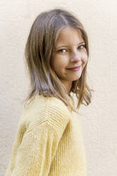 Smiling blond girl standing in front of wall - LMCF00703