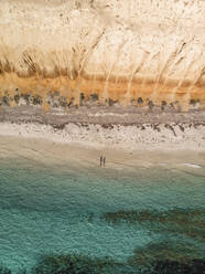 Aerial view of Balgowan beach with orange cliffs and turquoise water and two people casting a shadow on the beach, top down perspective, Yorke Peninsula, South Australia. - AAEF23997