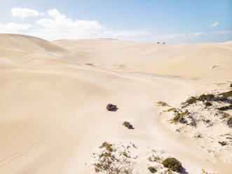 Aerial view of a car driving on sand dunes in Port Lincoln National Park, South Australia. - AAEF24002