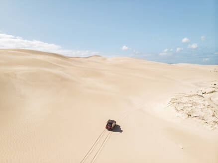 Aerial view of a car driving on sand dunes in Port Lincoln National Park, South Australia. - AAEF24004