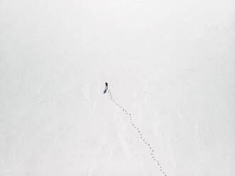 Aerial view a person standing on an empty salt flat with footprints leading up to the person, South Australia. - AAEF24013