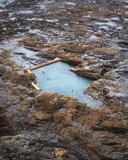 Aerial view of Trevone natural sea pool with people cold water swimming in autumn, Trevone Bay, Cornwall, United Kingdom. - AAEF24051