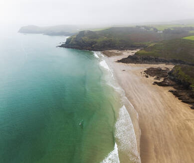 Aerial view of Lunday Bay at low tide, misty morning watching swimmer, Port Quin, Cornwall, United Kingdom. - AAEF24057