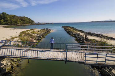 Luftaufnahme einer Person auf der Brücke über den Fluss Dyavolska, der ins Meer mündet, Primorsko, Provinz Burgas, Bulgarien. - AAEF24119