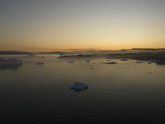 Aerial drone view of the iceberg lagoon at Ilulissat at a foggy golden morning, Greenland, Arctic. - AAEF24170