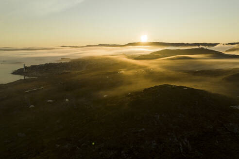 Drohnenaufnahme der Landschaft um die Stadt Ilulissat in Grönland, die bei Sonnenaufgang in Nebel gehüllt ist, Arktis. - AAEF24179