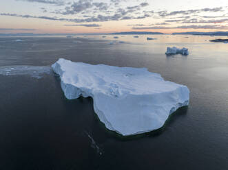 Aerial drone view of a huge iceberg at the Ilulissat ice fjord lagoon in Greenland at morning blue hour, Arctic. - AAEF24199