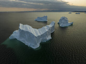 Aerial drone view of gigantic icebergs in Ilulissat at dawn, Greenland, Arctic. - AAEF24204