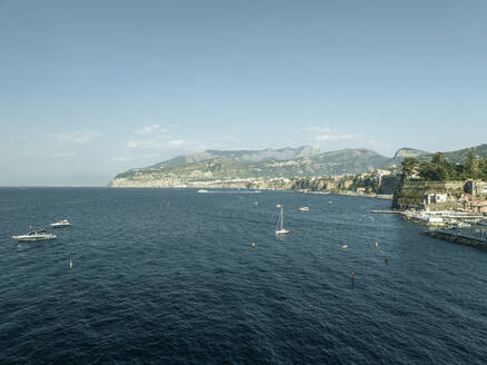 Aerial view of sailing boat along the coast in Sorrento Bay near the harbour, Naples, Campania, Italy. - AAEF24234