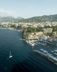 Aerial view of sailing boat along the coast in Sorrento Bay near the harbour, Naples, Campania, Italy. - AAEF24261