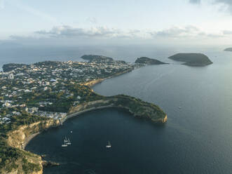 Luftaufnahme von Cala del Vecchio Pozzo mit der Insel Vivara im Hintergrund, einer kleinen Bucht mit hohen Klippen auf der Insel Procida bei Sonnenuntergang, Flegree Islands Archipel, Neapel, Kampanien, Italien. - AAEF24327