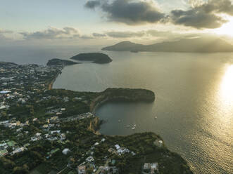 Luftaufnahme von Cala del Vecchio Pozzo mit der Insel Vivara im Hintergrund, einer kleinen Bucht mit hohen Klippen auf der Insel Procida bei Sonnenuntergang, Flegree Islands Archipel, Neapel, Kampanien, Italien. - AAEF24328