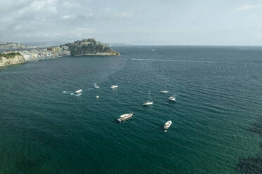 Luftaufnahme einiger Segelboote vor der Altstadt von Procida auf der Insel Procida mit dem Golf von Neapel im Hintergrund, Flegree Islands Archipel, Neapel, Kampanien, Italien. - AAEF24390