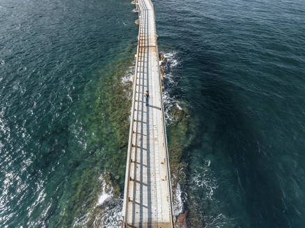 Luftaufnahme einer Frau, die auf der Vivara-Brücke spazieren geht, die das Naturschutzgebiet der Insel Vivara mit der Insel Procida verbindet, Archipel der Flegree-Inseln, Neapel, Kampanien, Italien. - AAEF24422